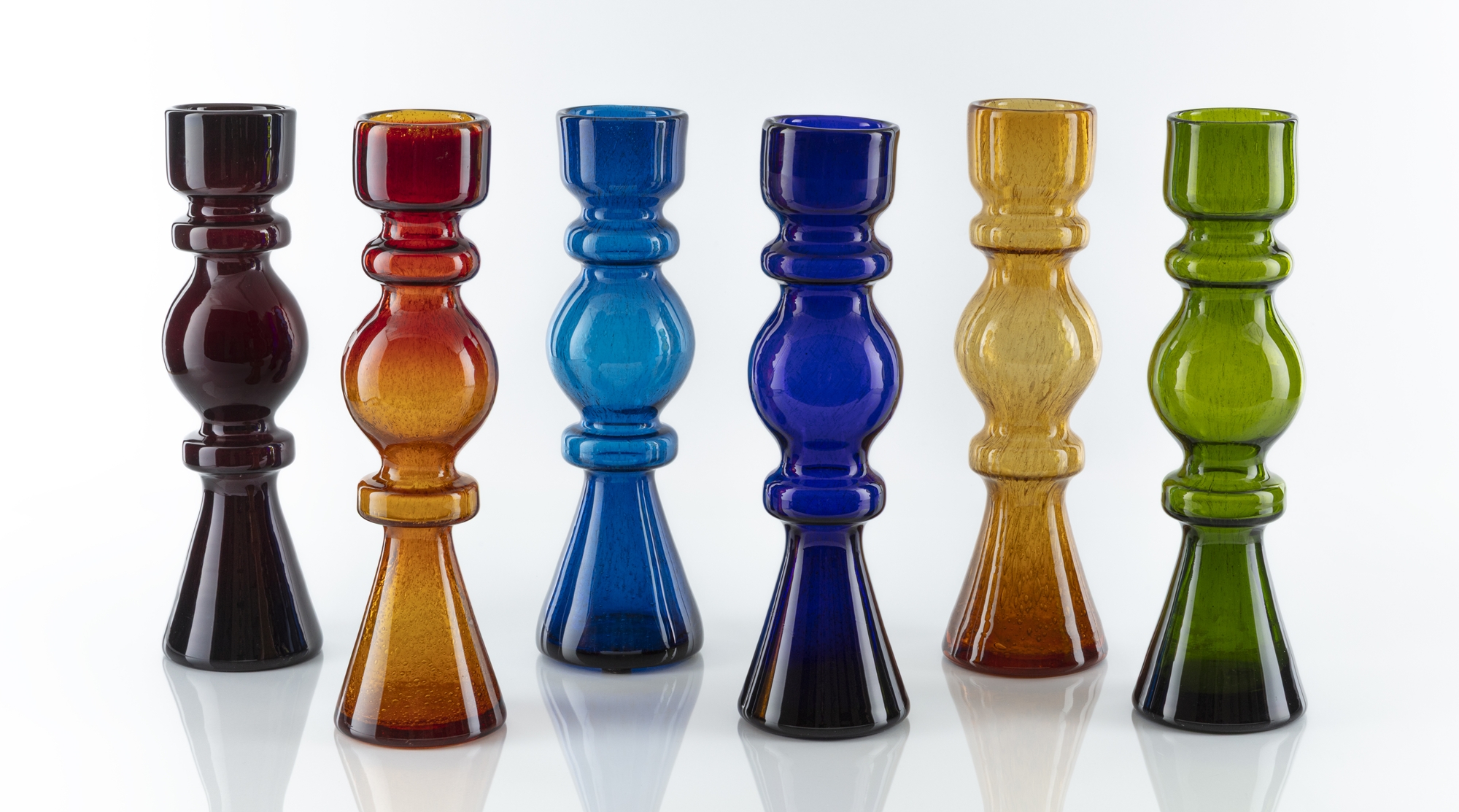 siedem wysokich wazonów w różnych kolorach stojących na białym tle