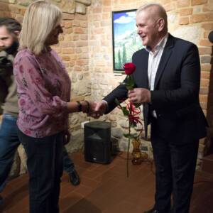 Dyrektor Muzeum Okręgowego w Tarnowie - Kazimierz Kurczab ściska dłoń kuratorce wystawy - Bożenie Szczupak, w lewej ręce trzyma czerwoną różę.