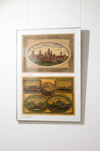 Dwa obrazy jeden pod drugim w jednej antyramie. u Góry obraz przedstawia miasto w złotej ramie, poniżej kolarz 5 mniejszych obrazków, również są namalowane krajobrazy z miastami wsiami i polami.