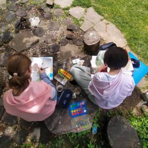Widok od góry. dwie dziewczynki malują małe obrazki siedząc w kamiennym kręgu.