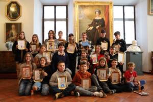 grupa dzieci z narysowaymi portretami pozuje do zdjęcia grupowego