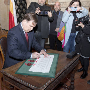 Mężczyzna składa podpis na dokumencie z pieczęciami w zielonej ramie.