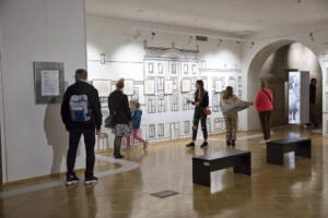 Grupa ludzi ogląda rysunki na wystawie w Muzeum Historii Tarnowa i Regionu
