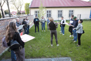 Grupa ludzi na placu za Regionalnym Centrum Edukacji o Pamięci biorą udział w zajęciach z historii Polski.