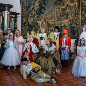 Grupa młodzierzy w strojach średniowiecznych - królowie księżniczka, paź. Pozują do zdjęcia grupowego.