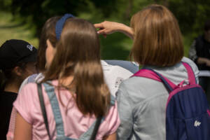 zdjęcie od tył na dziewczynki trzymające mapę i wskazujące kierunek ręką