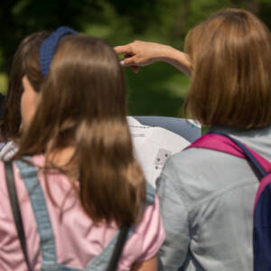 zdjęcie od tył na dziewczynki trzymające mapę i wskazujące kierunek ręką